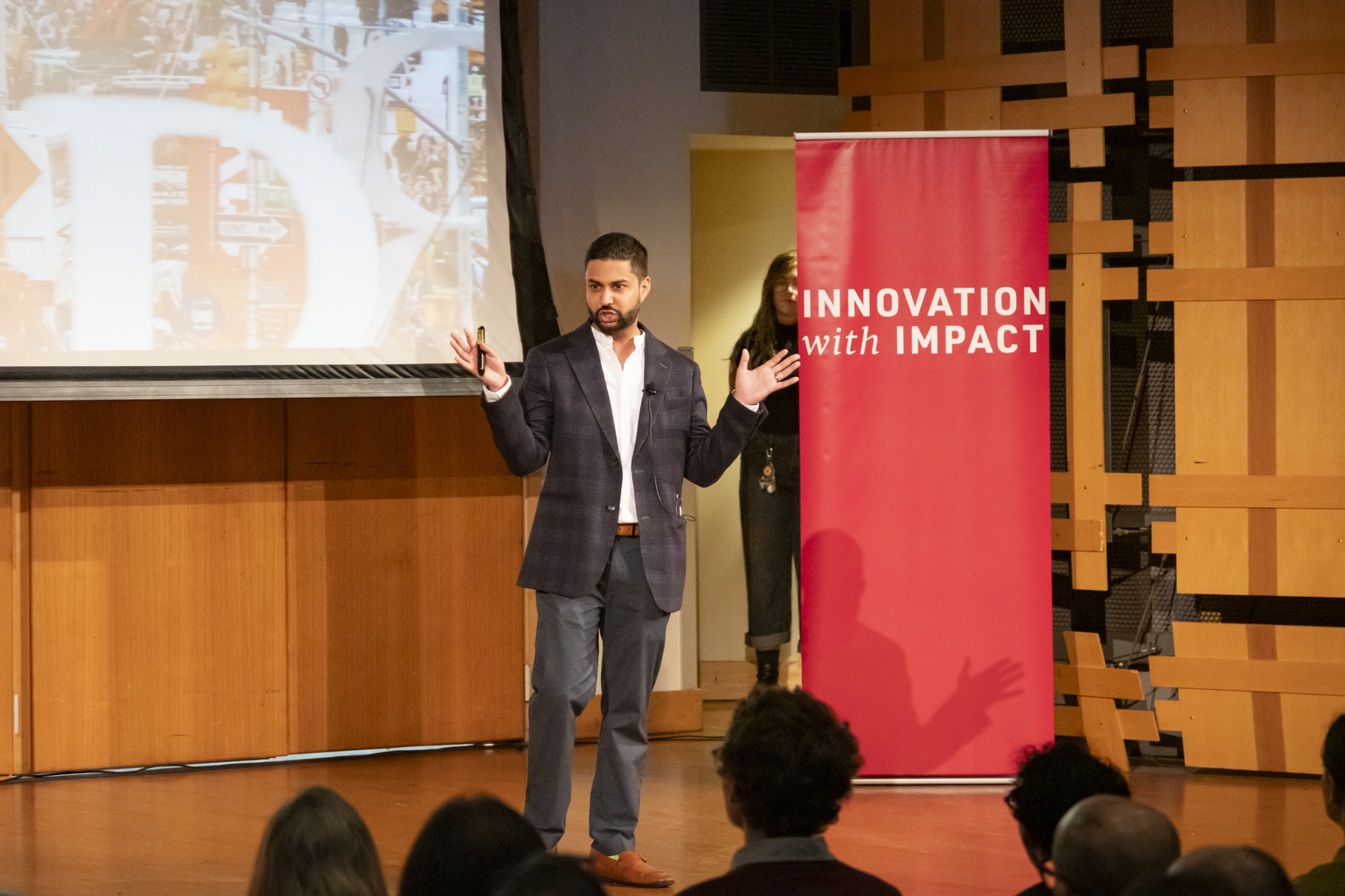 Professor stand on a stage next to Innovation with Impact sign