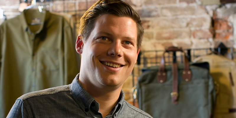 Brian Linton sitting among United by Blue apparel.