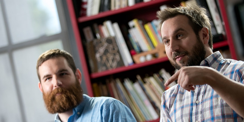 Two male Temple alumni working in their graphic design studio.