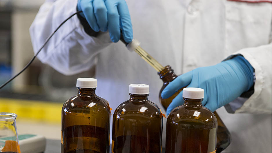 A scientist s hand dropping liquid into test bottles.
