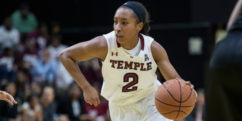 A women's basketball player dribbling the ball up the court.