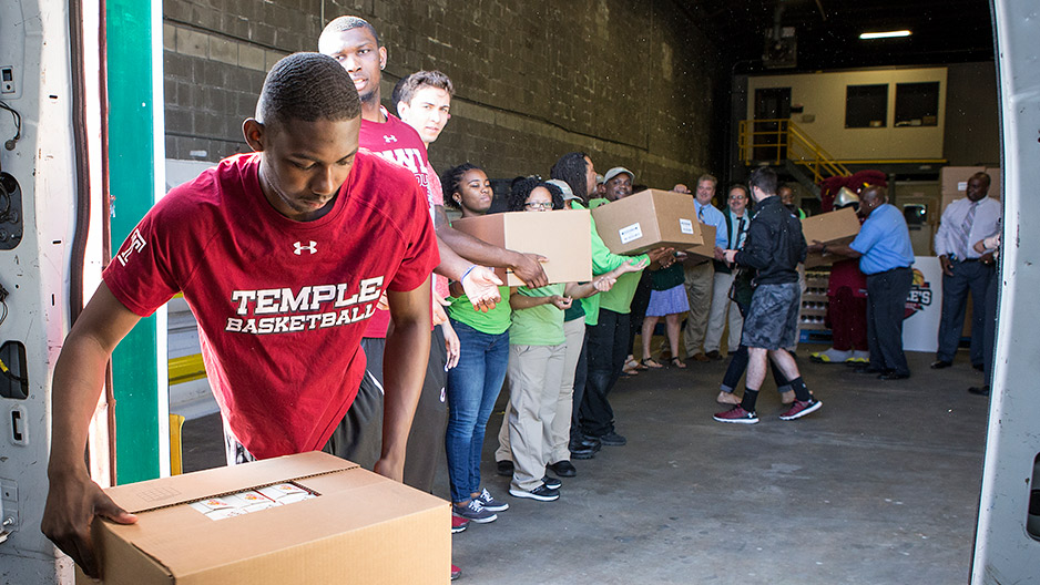 Temple men s basketball players unloading a van at a food bank.