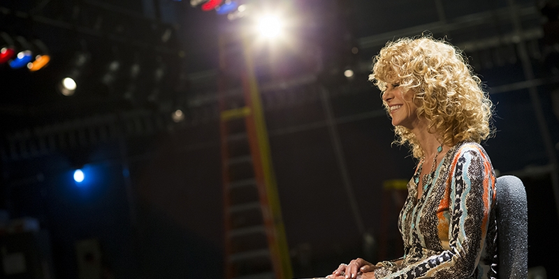 Sharon Pinkenson smiling as she sits on a stage.