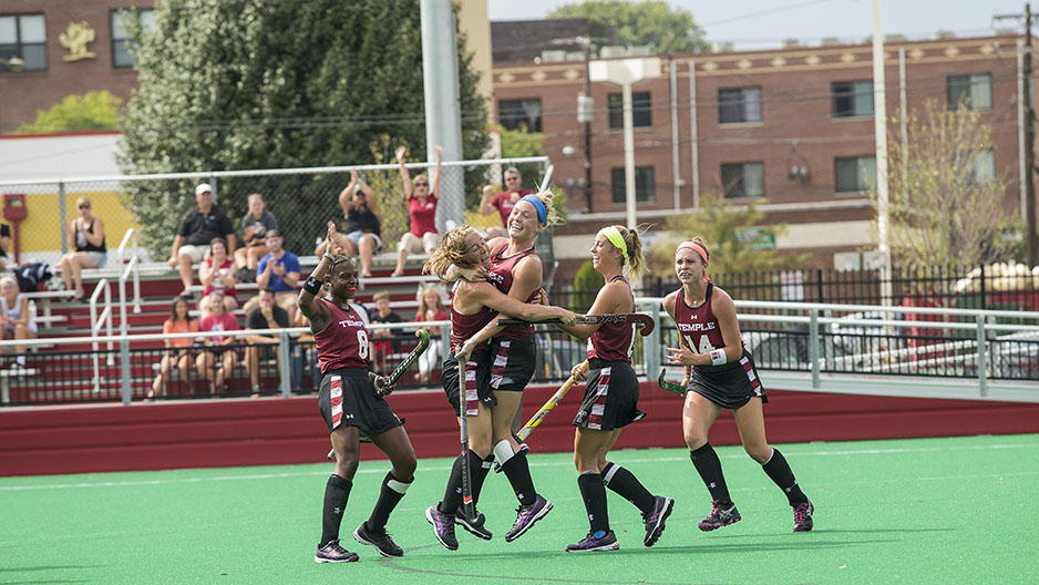 Temple s field hockey team celebrating on the field.