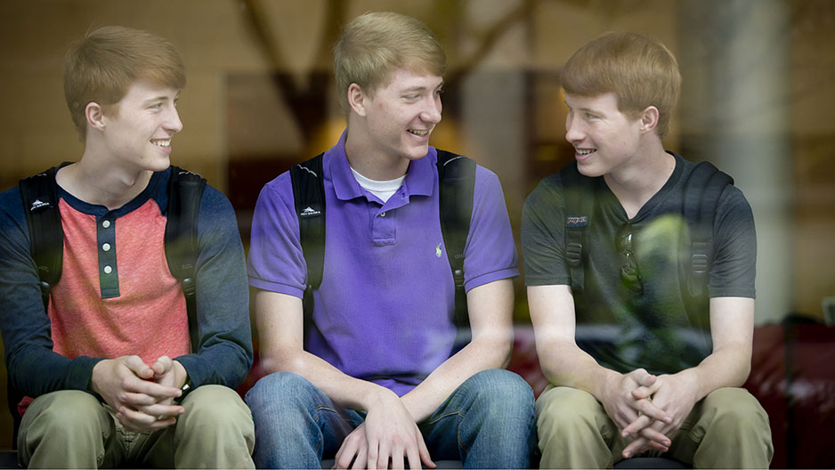 Three young men sitting and talking together.