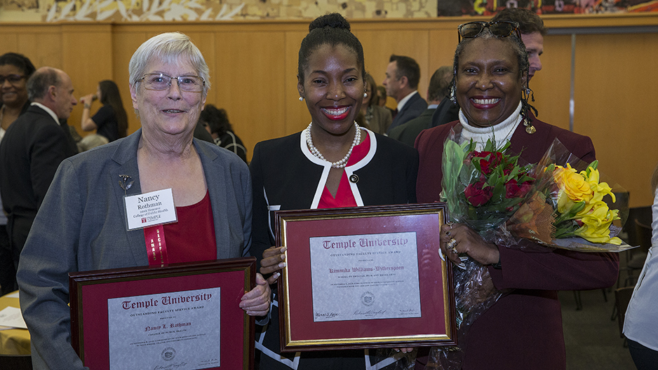 Two women holding awards and one woman holding flowers.