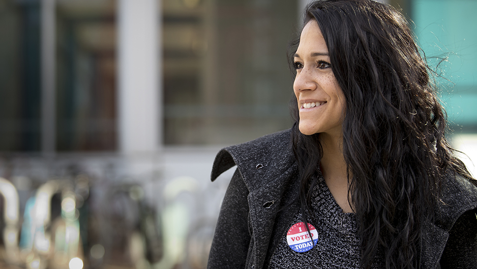 A woman smiling with an I voted sticker on her shirt.