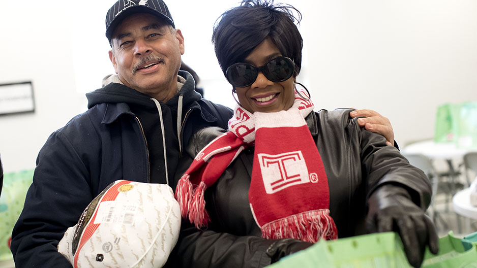 a man and a woman smiling and holding a frozen turkey.