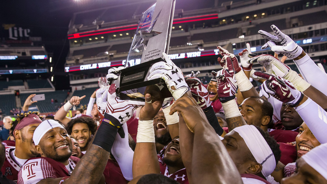 Temple s football team holding the AAC East Conference Division title trophy.