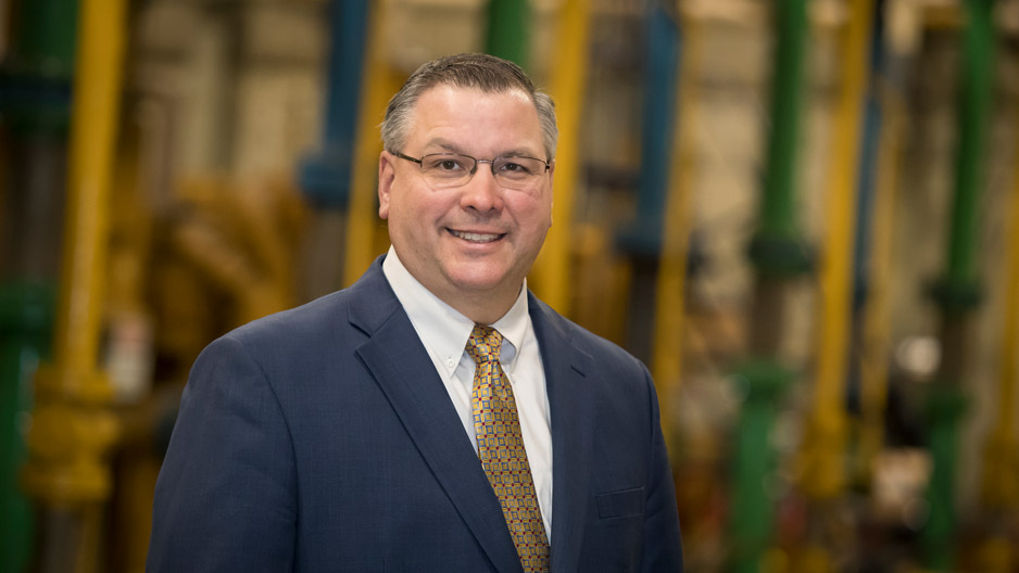 A man standing in front of a row of generators inside Temple University s generator room.