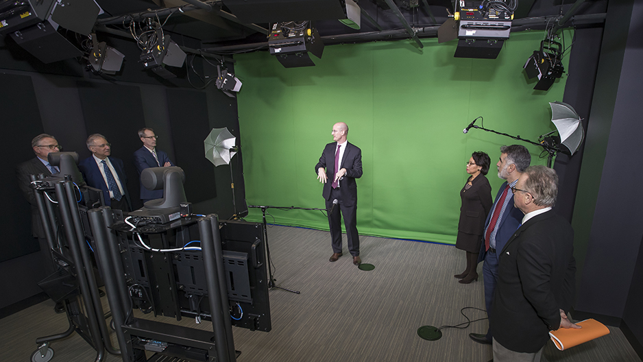A group of administrators looking at the green screen set up in the film studio.