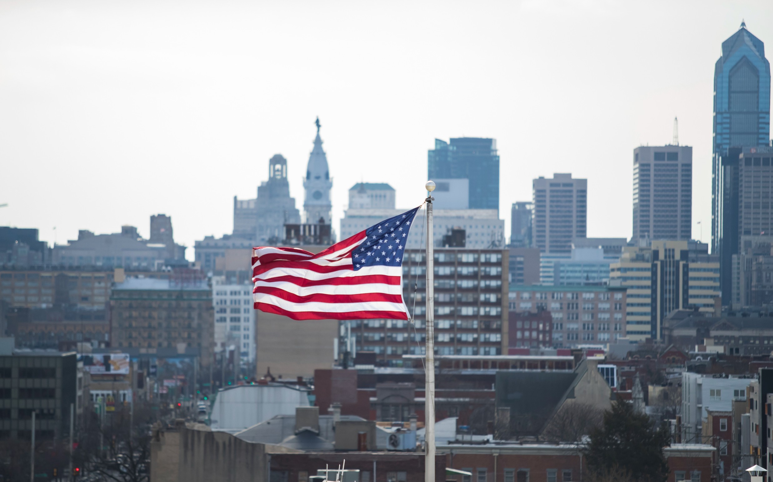 Image of an American flag in front of the Philadelphia skyline.