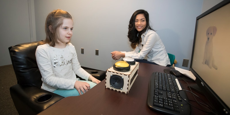 graduate student Zoe Ngo working with a child at a computer.