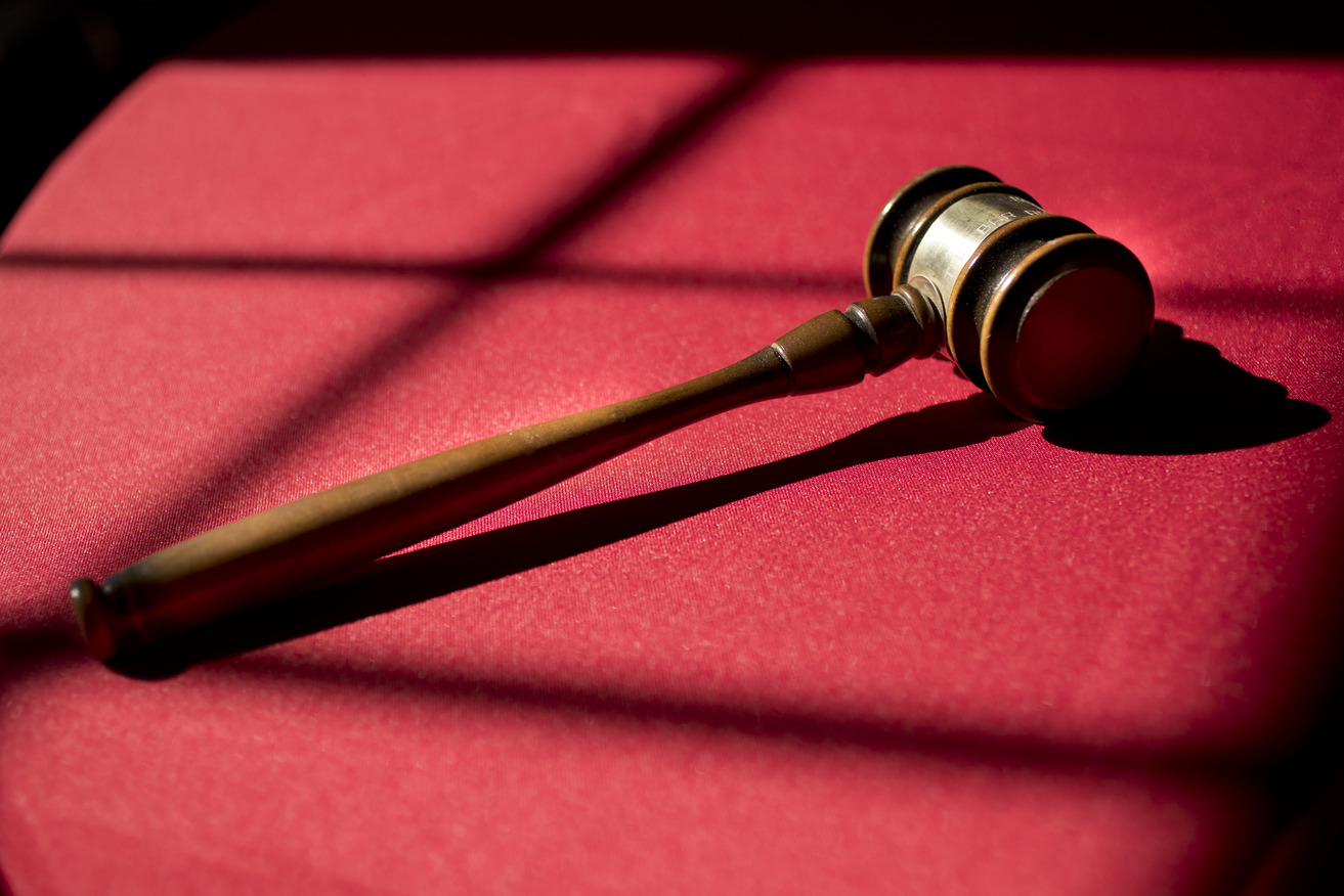 Image of a gavel placed on a table with red cloth.