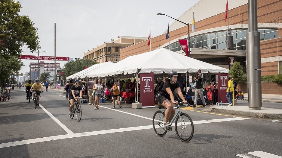 People riding bikes past Camp T on North Broad Street.
