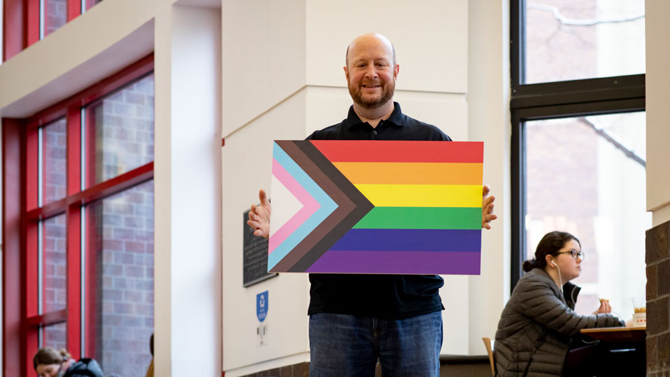 Jason Levy holding the Progress Pride flag