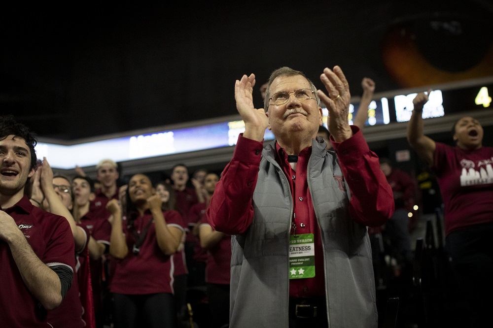 President Richard M. Englert clapping in the stands among Temple students at a basketball game.