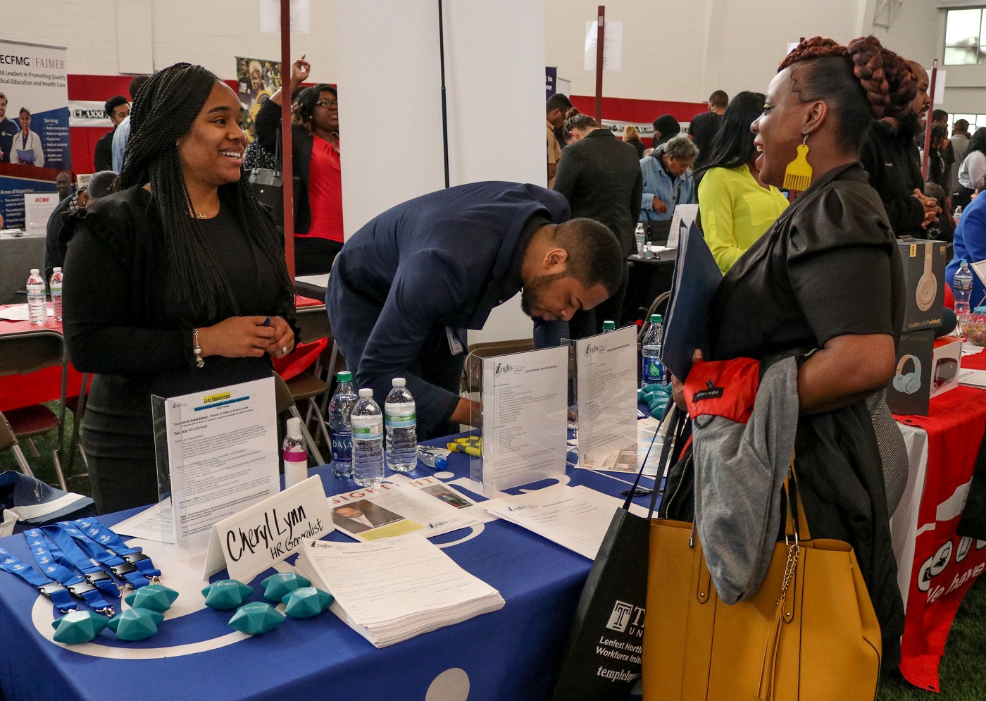 A group of people standing around a table during a job fair at Temple University.