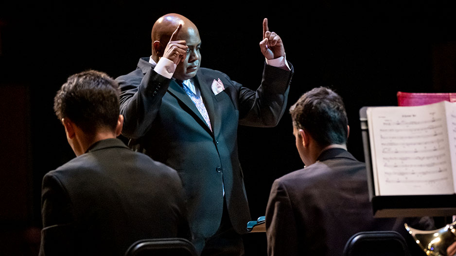 conductor standing in front of several members of the jazz band