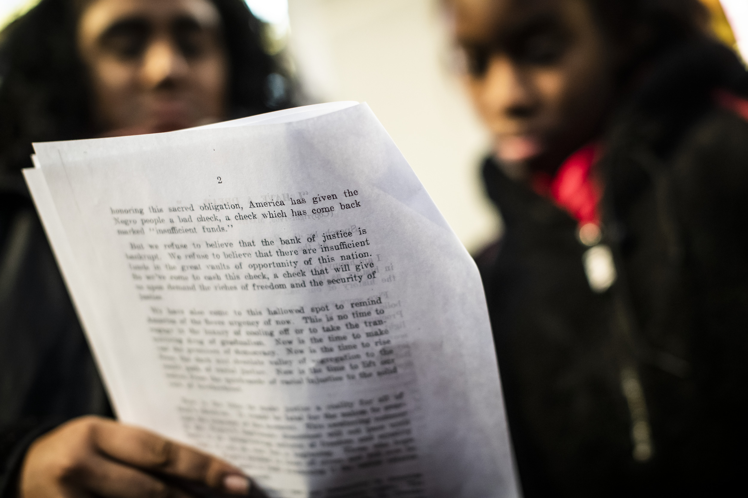 Two Black women read a page from a document together.