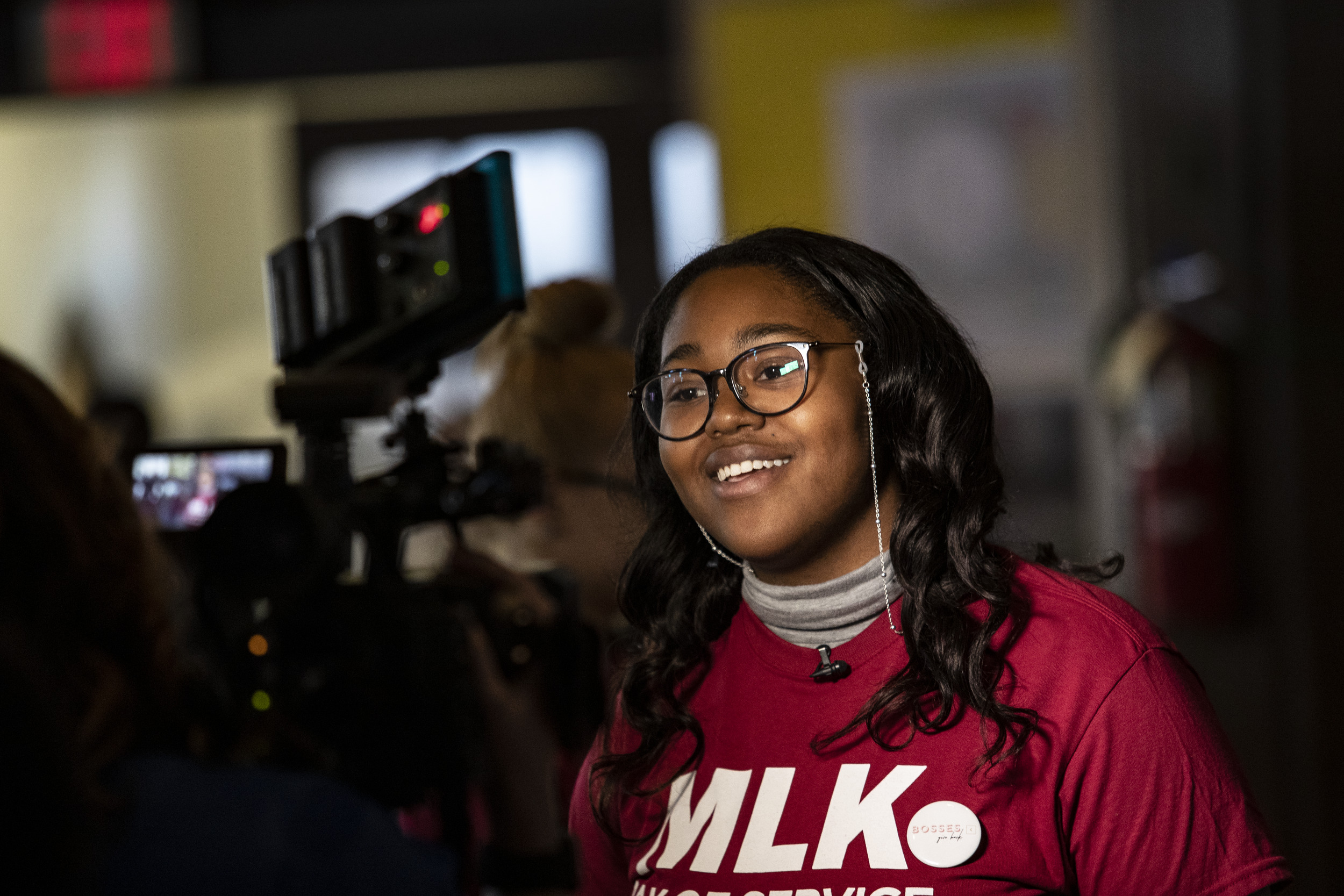Image of a Black woman wearing a cherry and white MLK Day shirt.