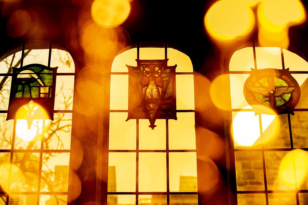 The sun shining through the stained glass windows of Mitten Hall's Great Court.