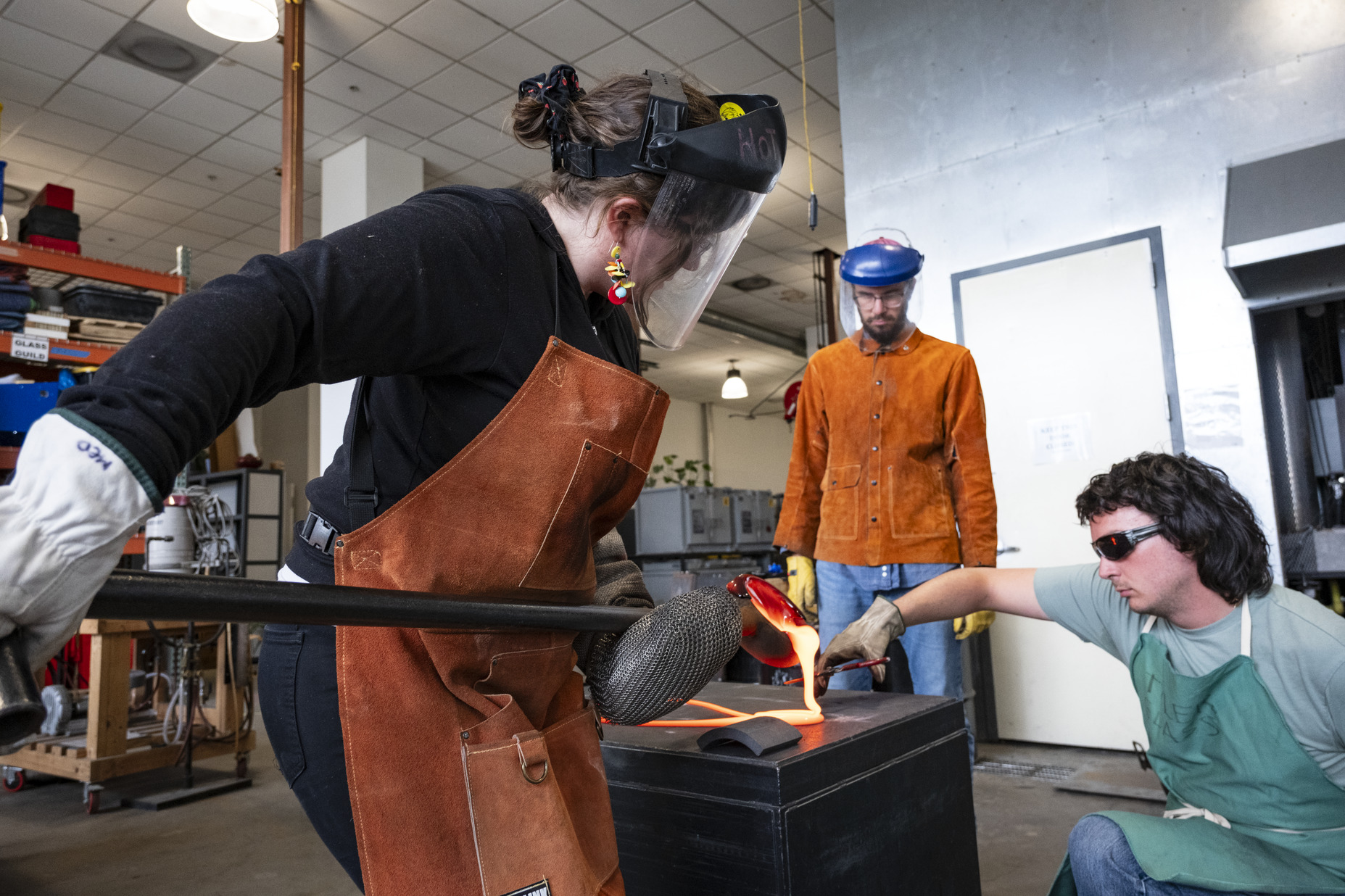 Image of Jessica Jane Julius and two helpers working with molten glass.