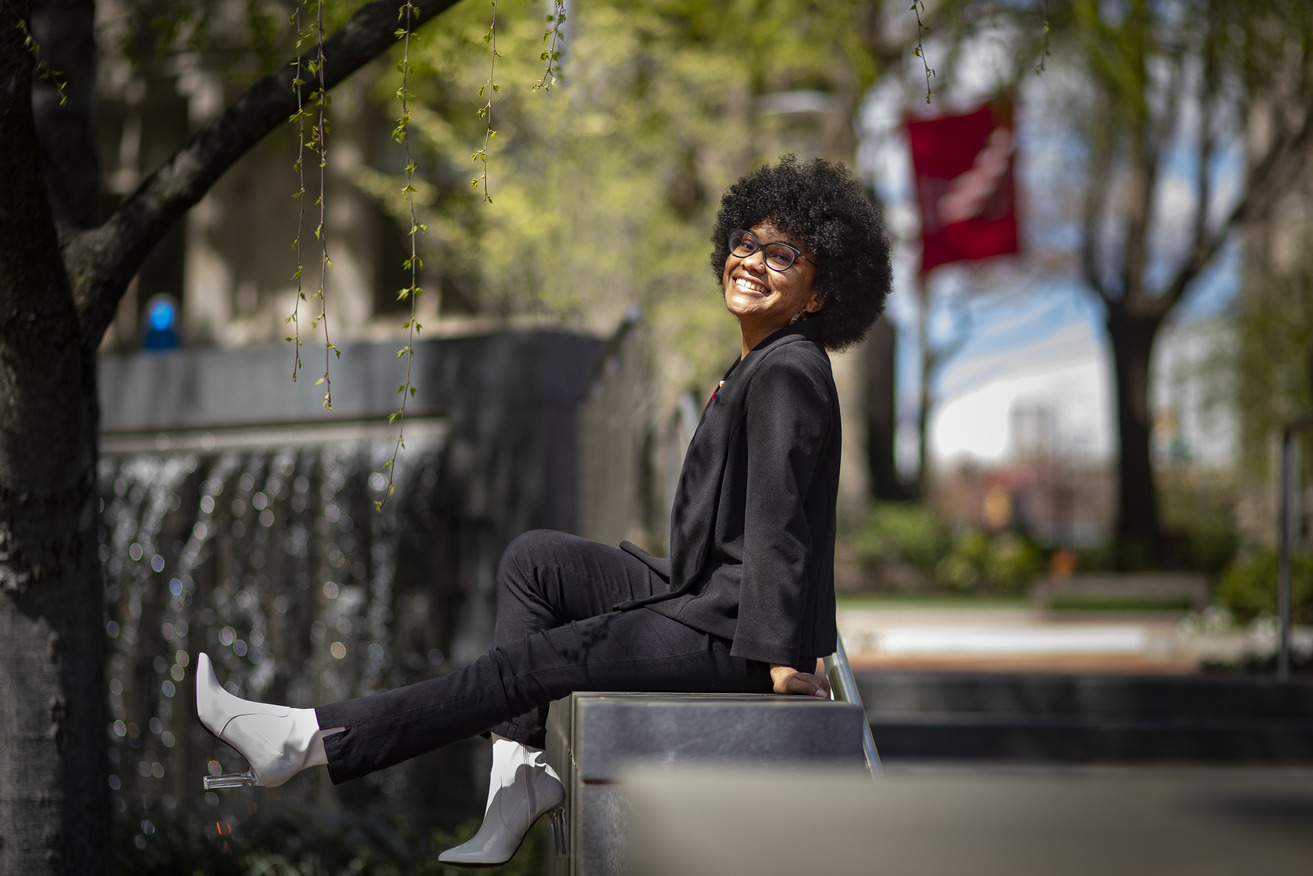 Hall sitting on a railing, kicking out her legs and grinning.