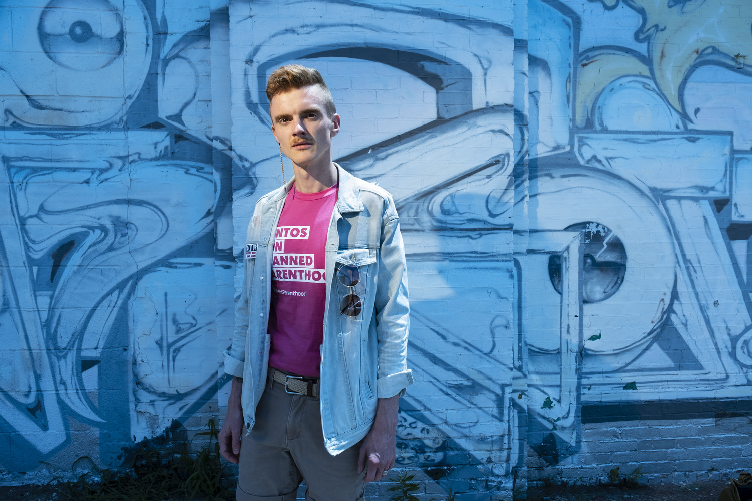 Andreas Copes in front of a blue background, wearing a Planned Parenthood shirt.