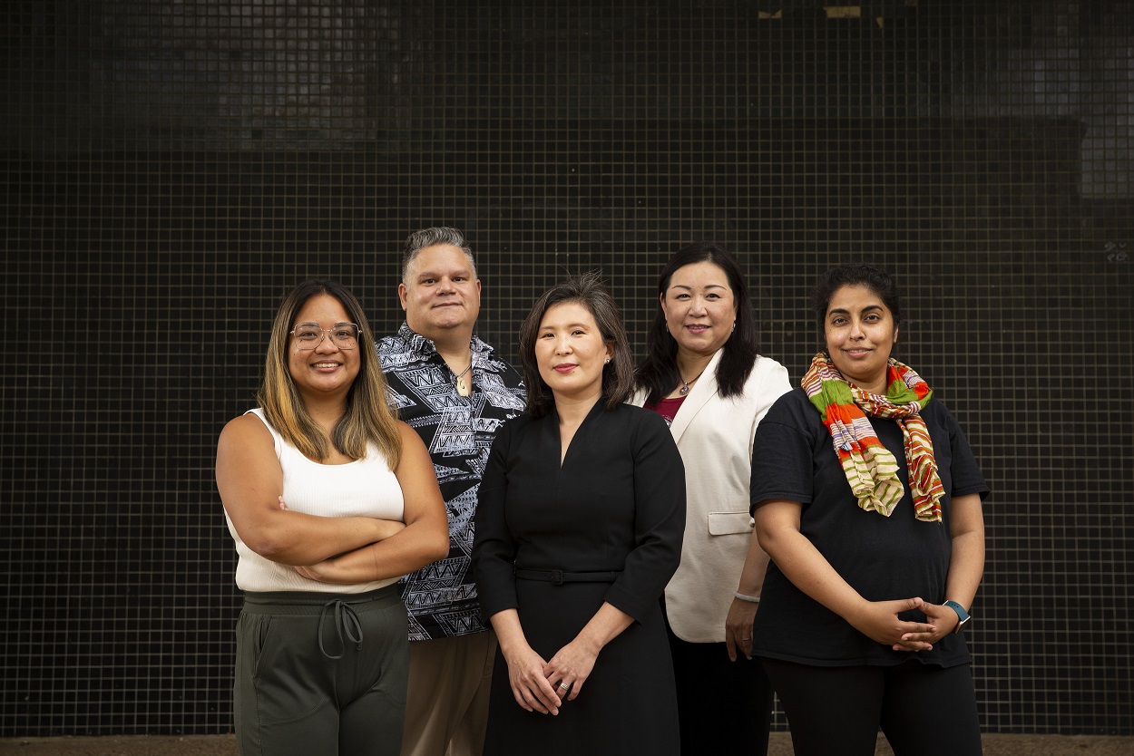 A group of Temple staff members standing in front of a black tiled wall.