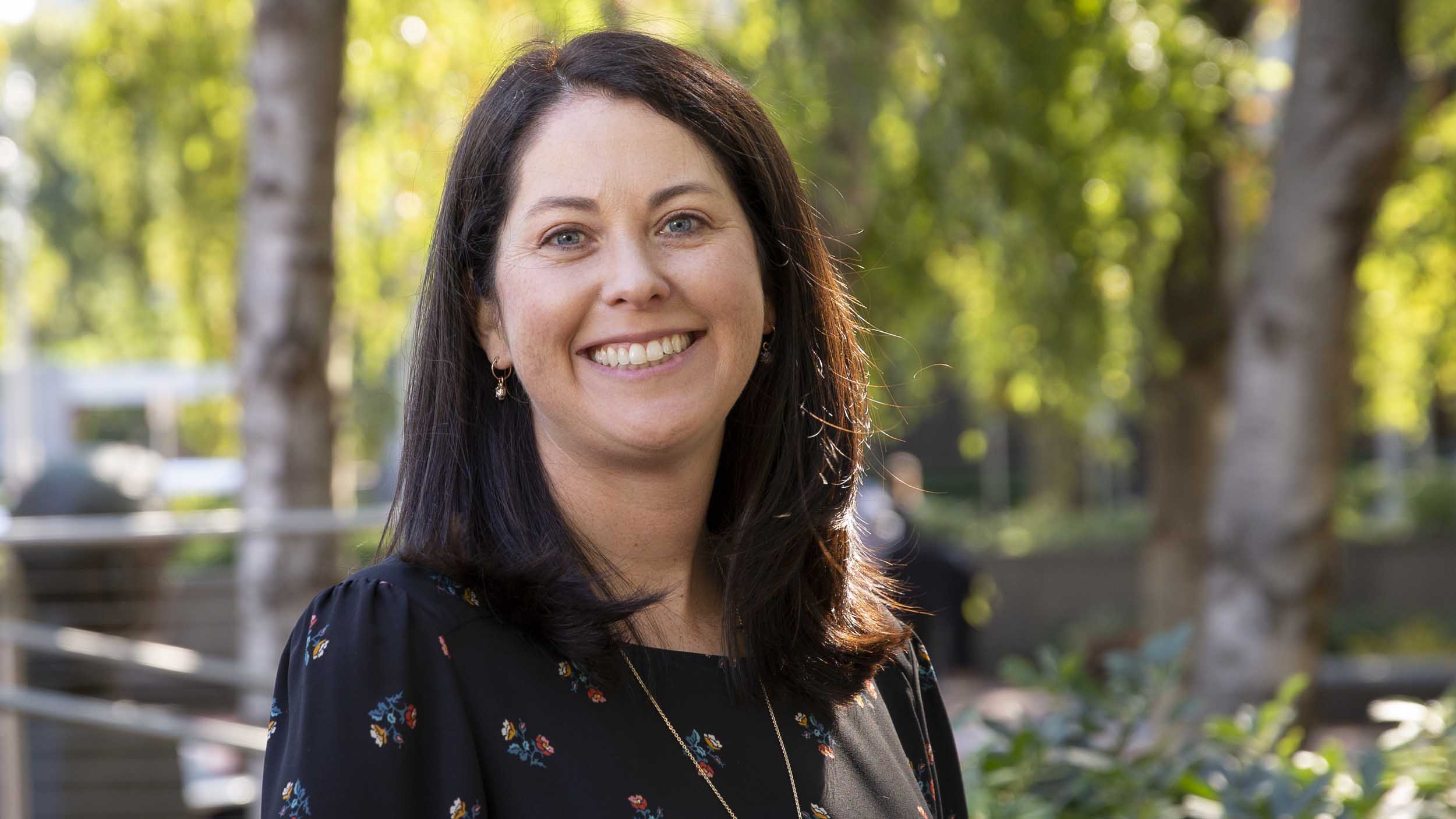 Juliet Curci wearing a navy blue blouse and smiling