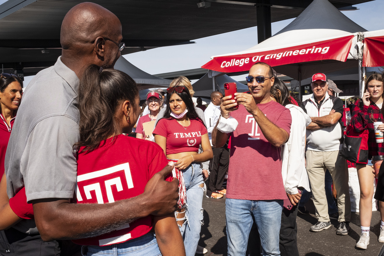 Image of Jason Wingard with a girl wearing a Temple cherry and white tee shirt.