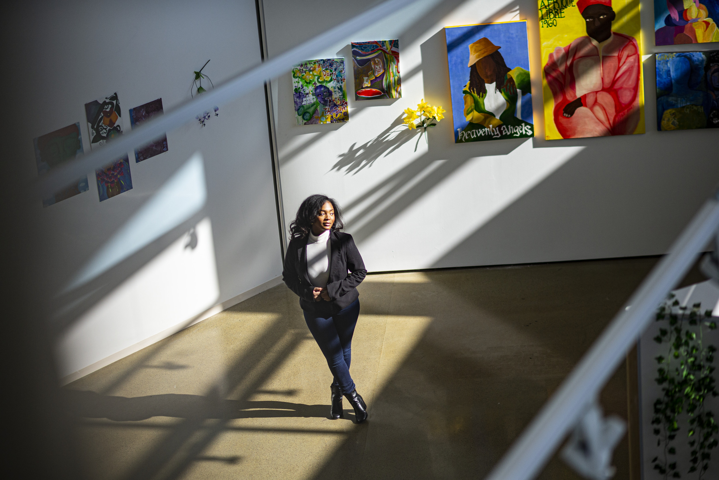 Image of Taylor Sanders standing in front of various paintings.