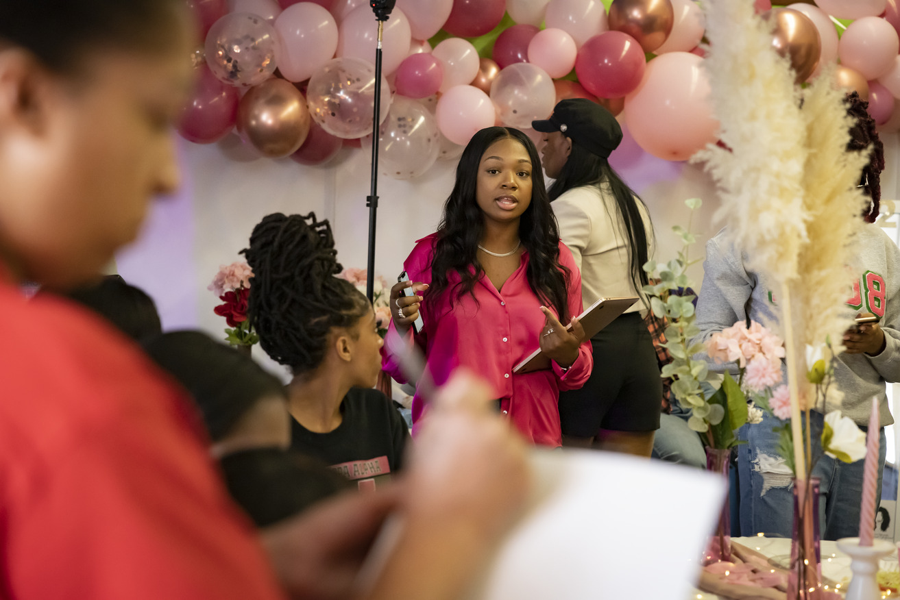 Image of Jaida Ragland wearing a pink blouse and standing in front of balloons