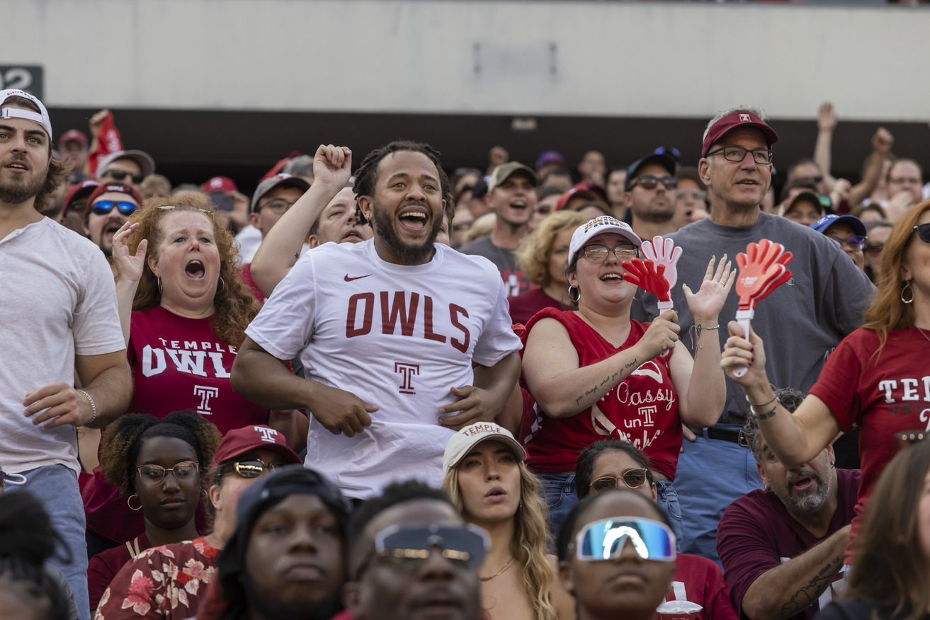 Image of a smiling college football fans wearing Temple-branded shirts.
