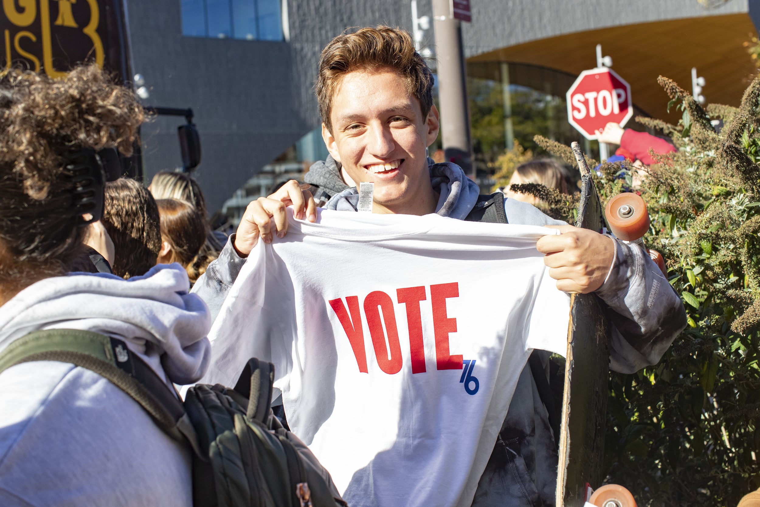 A Temple student holding a t-shirt that says vote