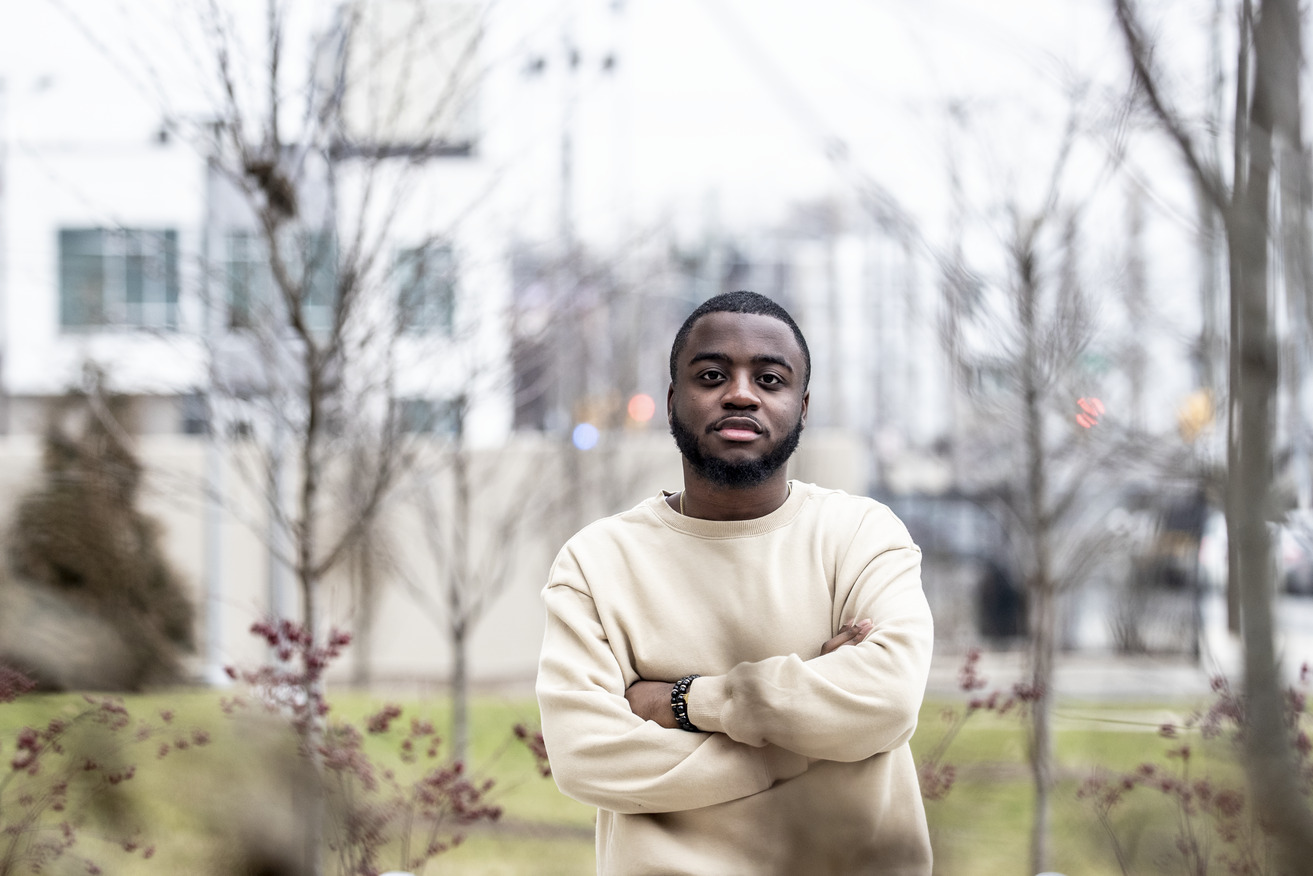 A student in a tan shirt outside in the streets of North Philadelphia.