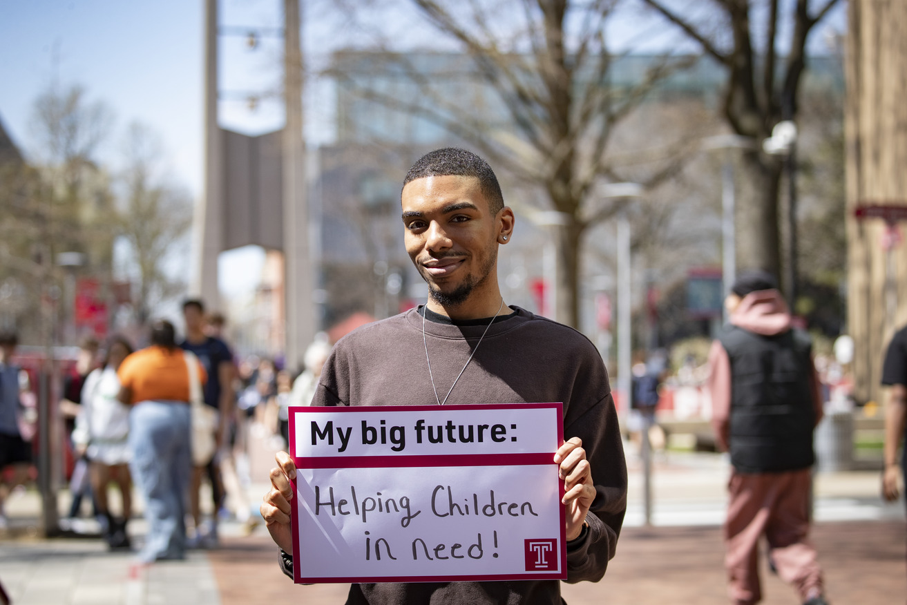 Cameron Barham holding a sign that says Helping Children in need
