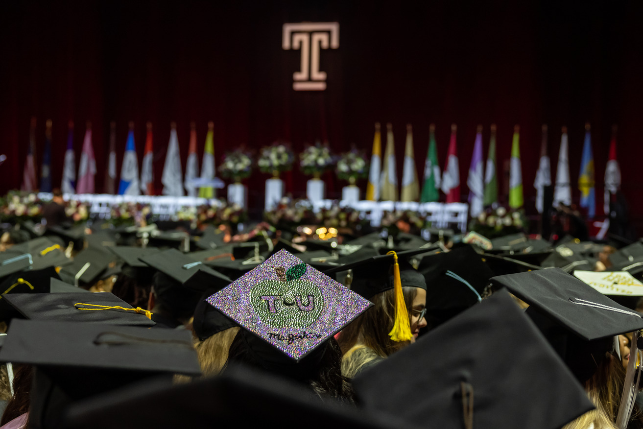 A crowd of graduates wearing caps looks towards the stage