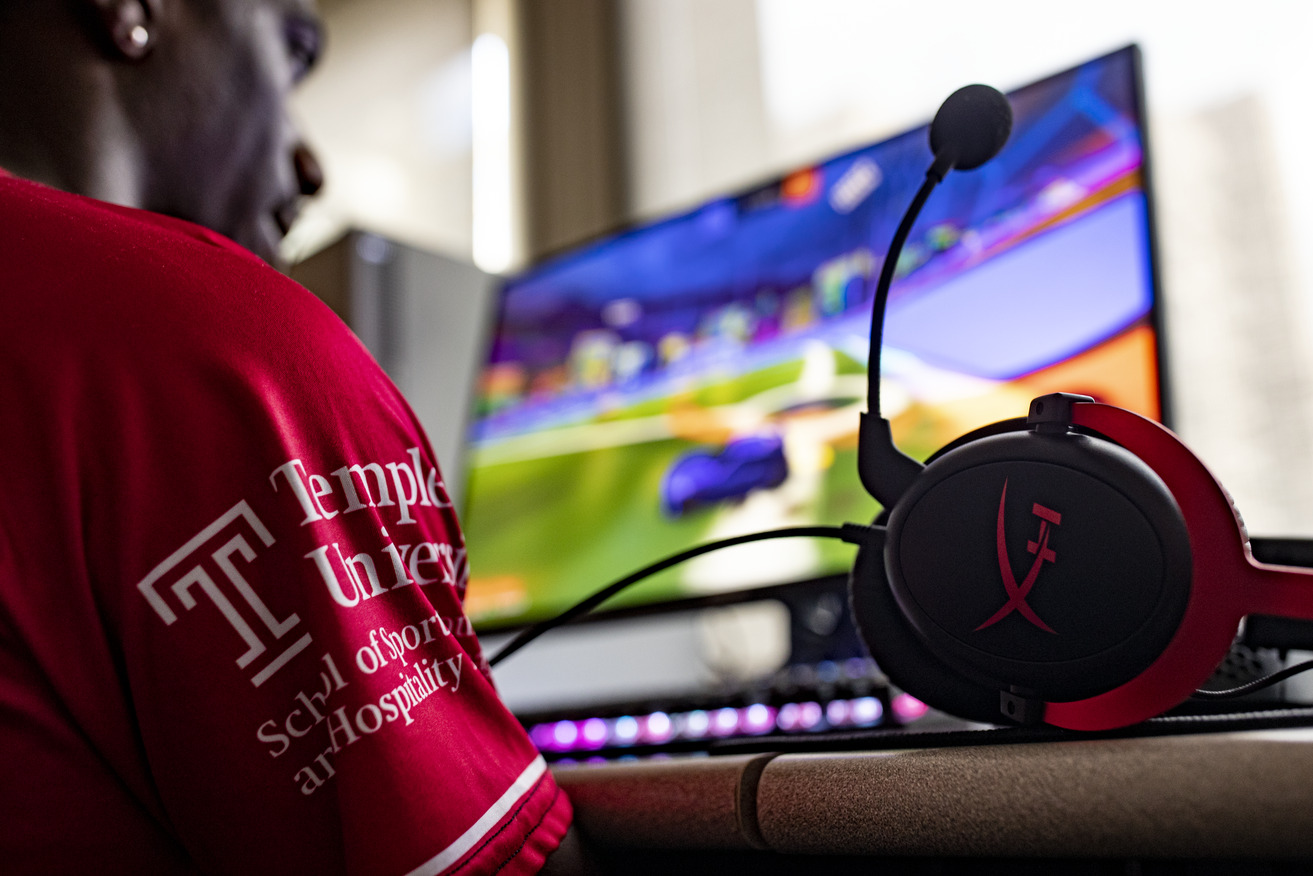 Image of a student wearing a Temple esports jersey playing a PC game.