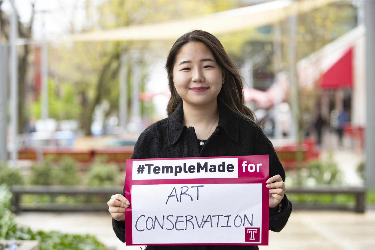 Image of Sera Park holding a sign reading #TempleMade for art conservation.