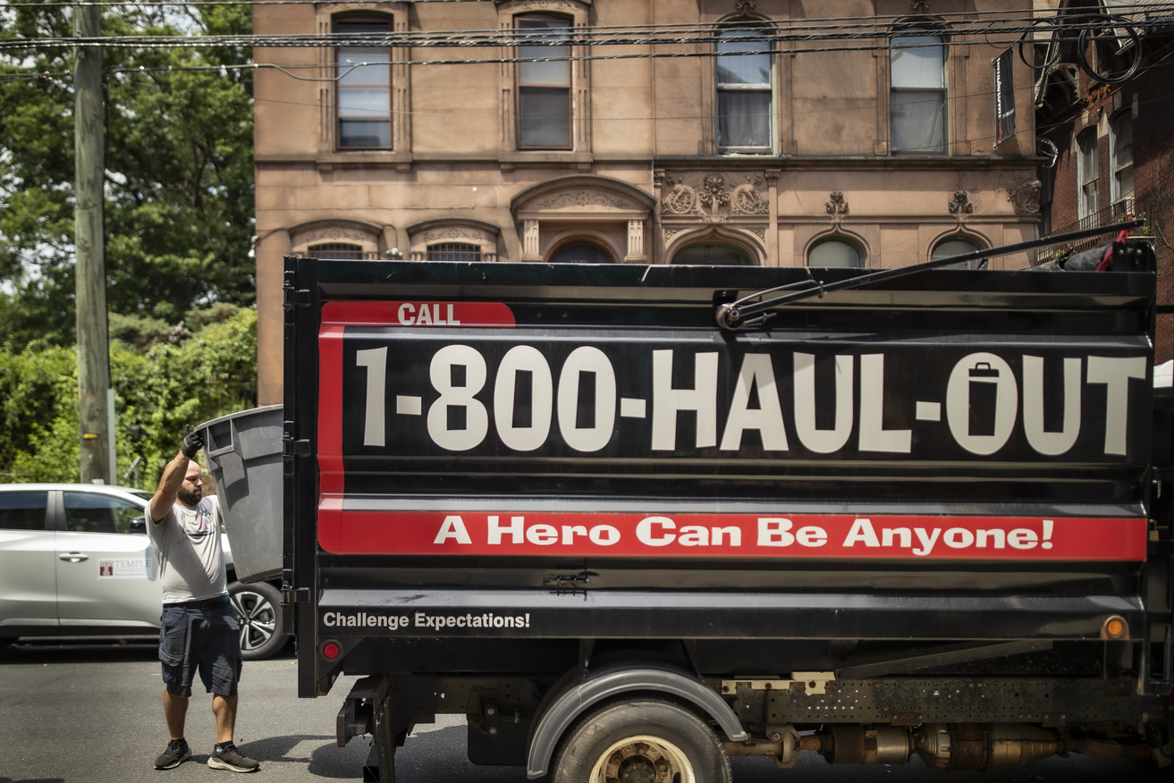 Image of a man wearing a gray shirt dumping trash in a pickup truck.