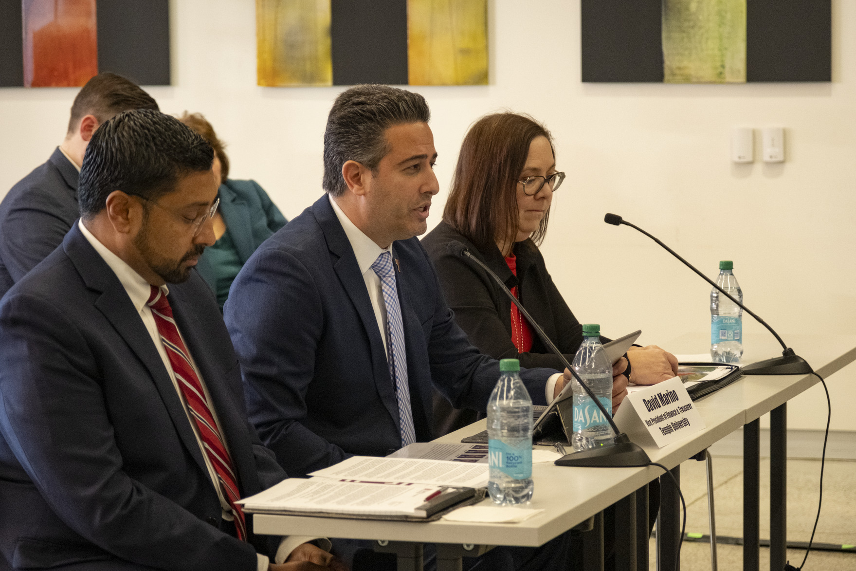 Individuals sitting at a table in front of small microphones
