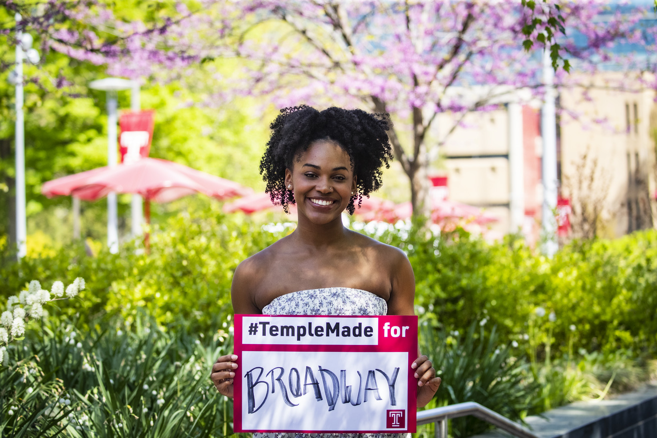 Jasmine Villaroel holding a Temple Made for sign outside on Main Campus