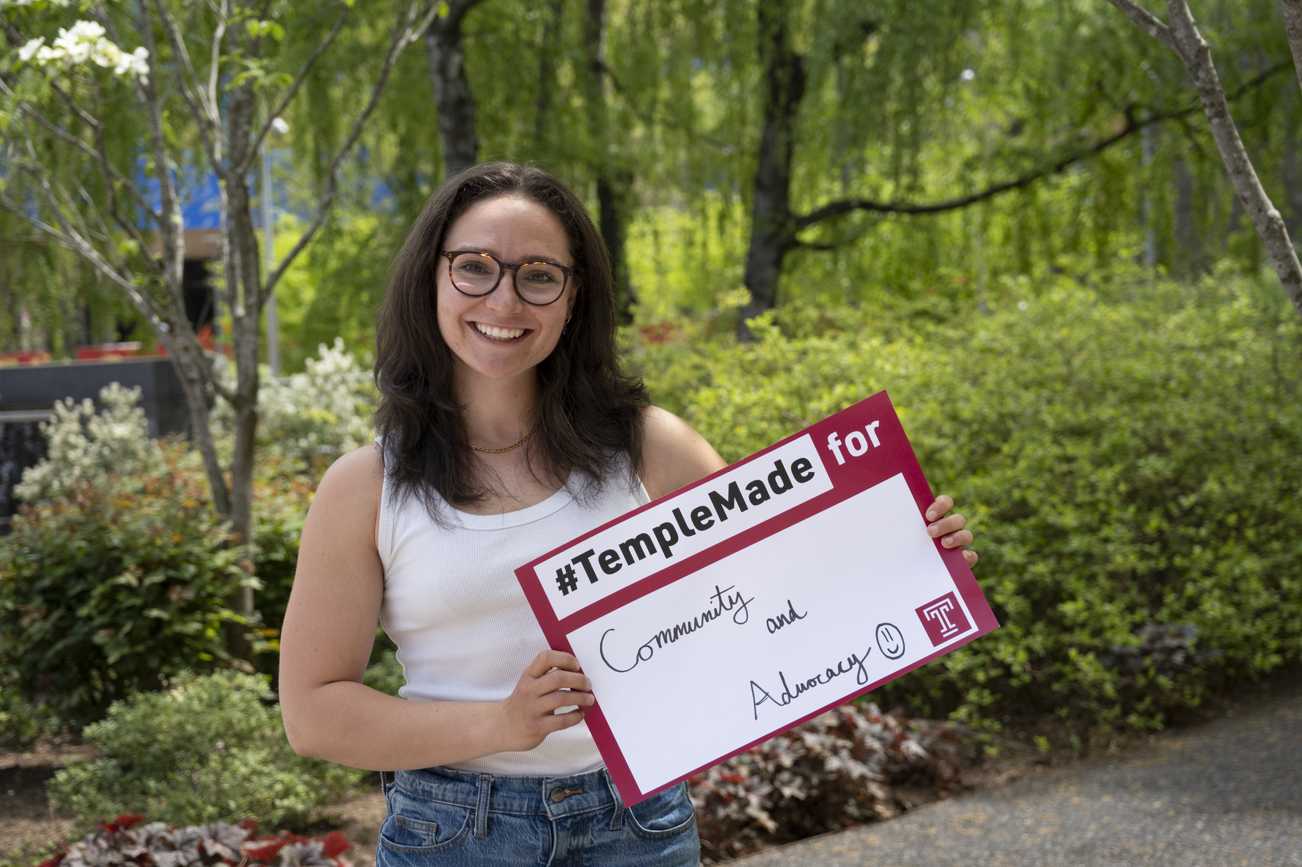 Trista Mayo standing outside holding up a Temple Made for sign