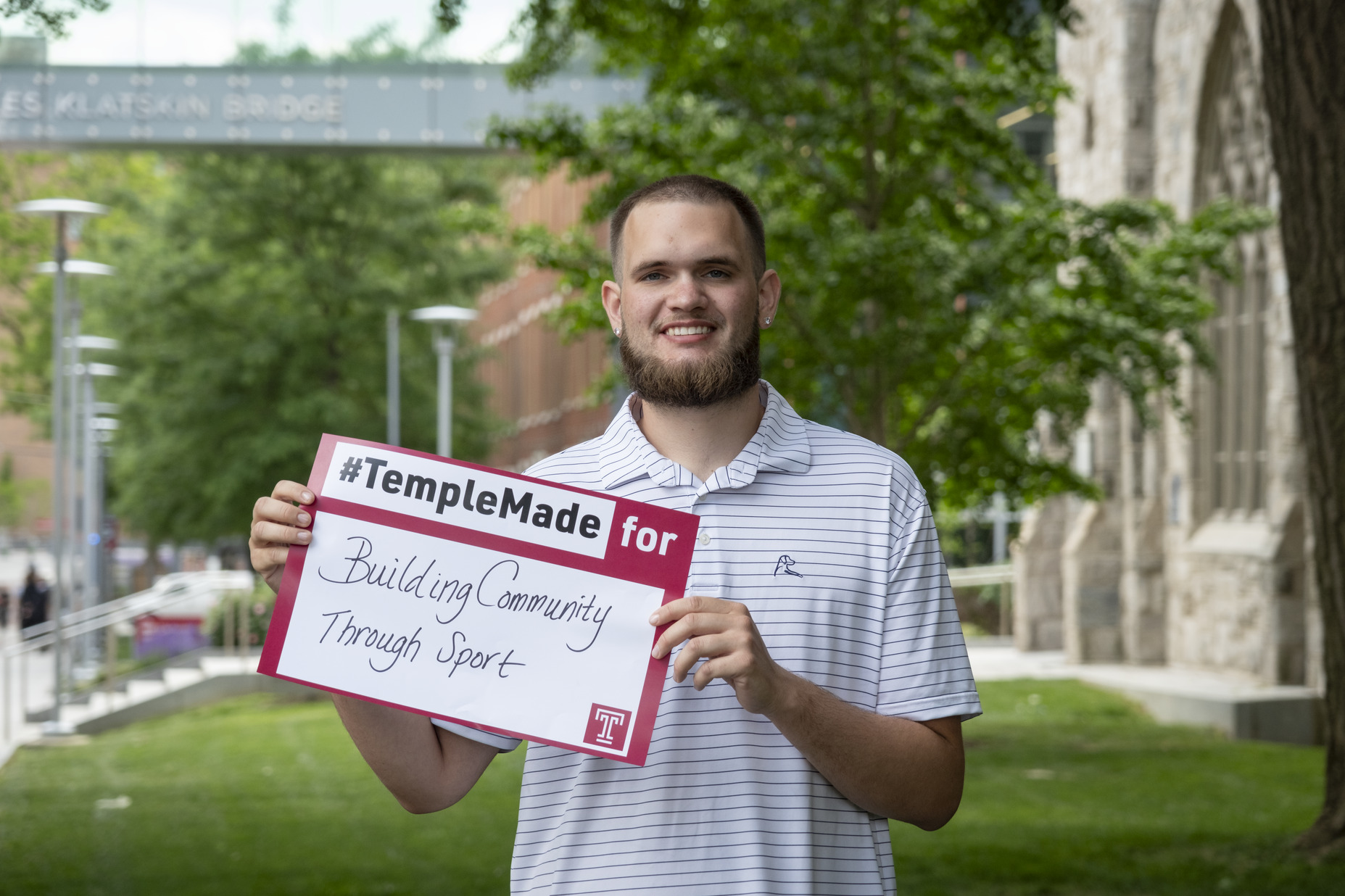 Ezekiel Cartwright standing outside holding up a Temple Made for sign