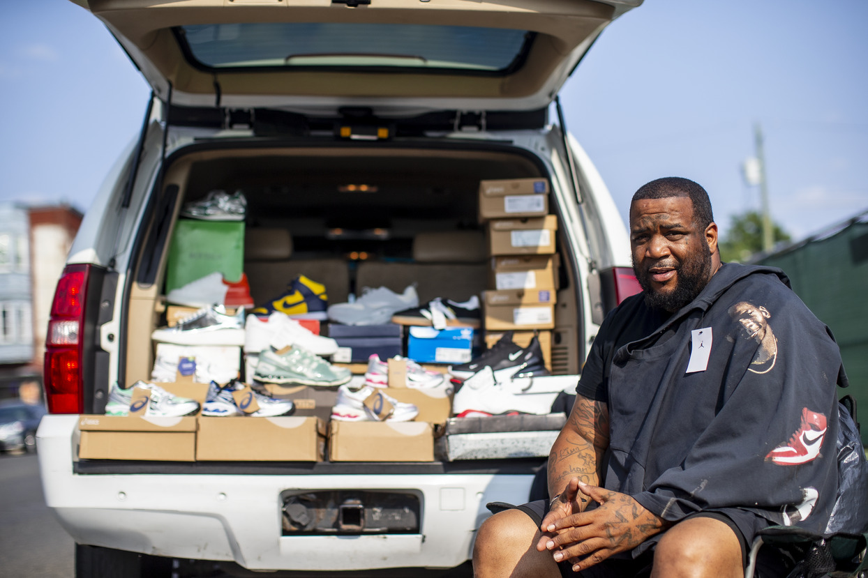 Image of a North Philadelphia resident in front of his truck load of sneakers.