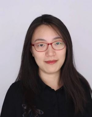 image of Jin wearing glasses and a black top smiling at the camera