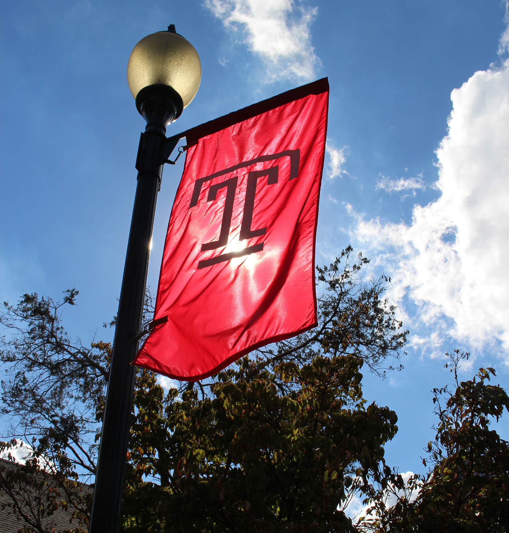 A view of the fall sun through the Temple T flag.