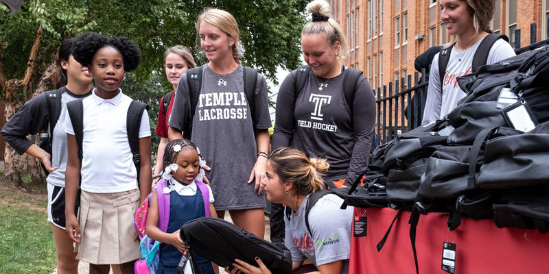 Temple student athletes distribute backpacks to local school students